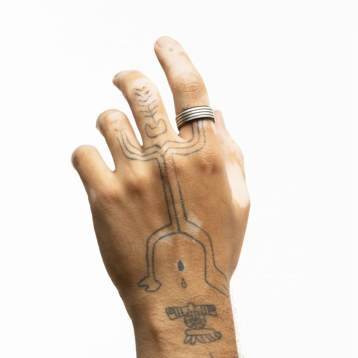 Zilverkleurige Lotus ring voor dames, gedragen op een hand met tatoeages.