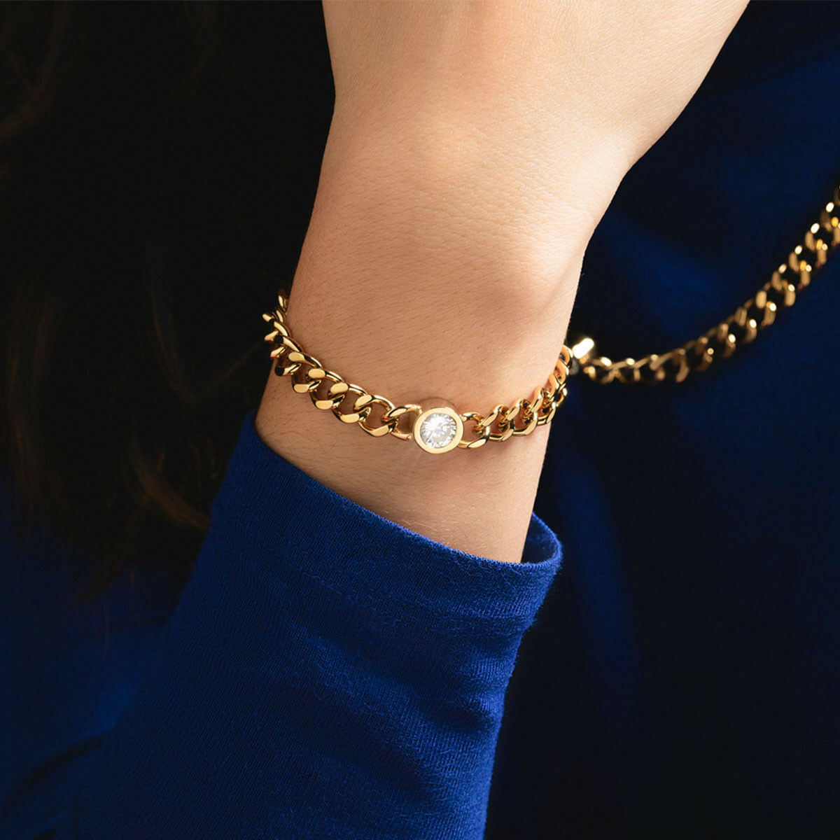 Detail van de gouden Lotus armband met een sprankelende steen, gedragen om een pols.