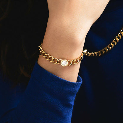 Detail van de gouden Lotus armband met een sprankelende steen, gedragen om een pols.