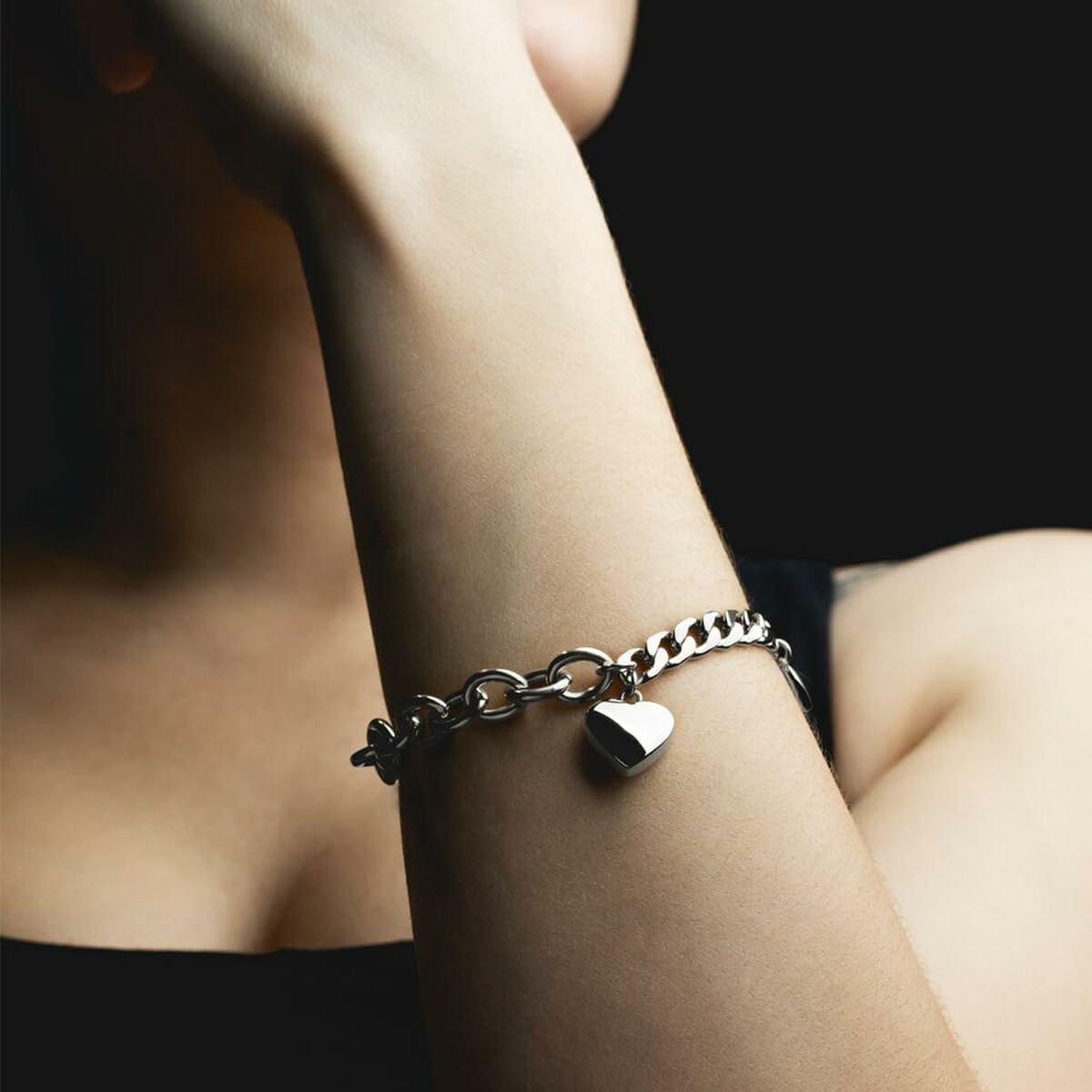 Zilverkleurige Lotus armband met hartvormige hanger, gedragen om de pols.
