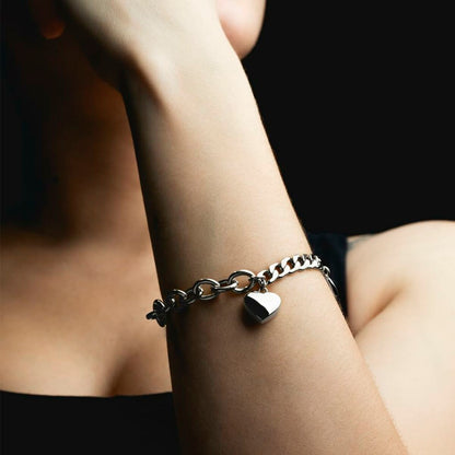 Zilverkleurige Lotus armband met hartvormige hanger, gedragen om de pols.