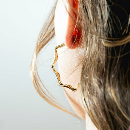 Detail van de gouden Lotus oorbellen met elegant design, gedragen aan een oor.