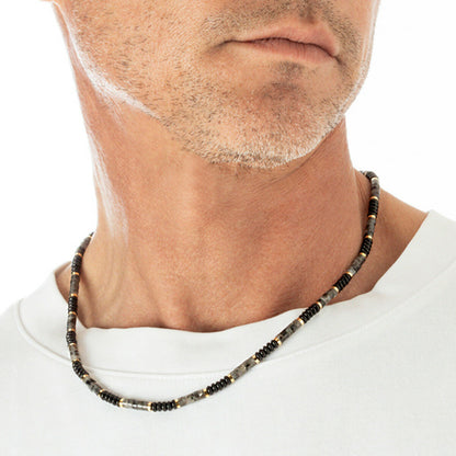 Detail van de Lotus ketting met elegante kralen in zwart en grijs, gedragen door een man.