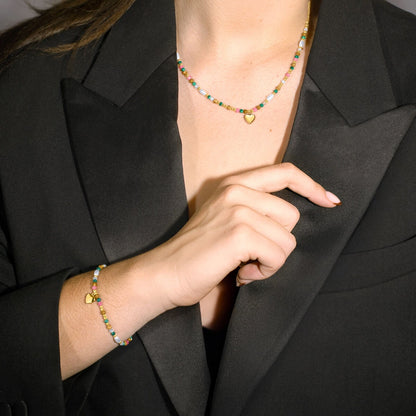 Detail van de Lotus multicolour ketting met hartje, gedragen met een zwarte blazer.