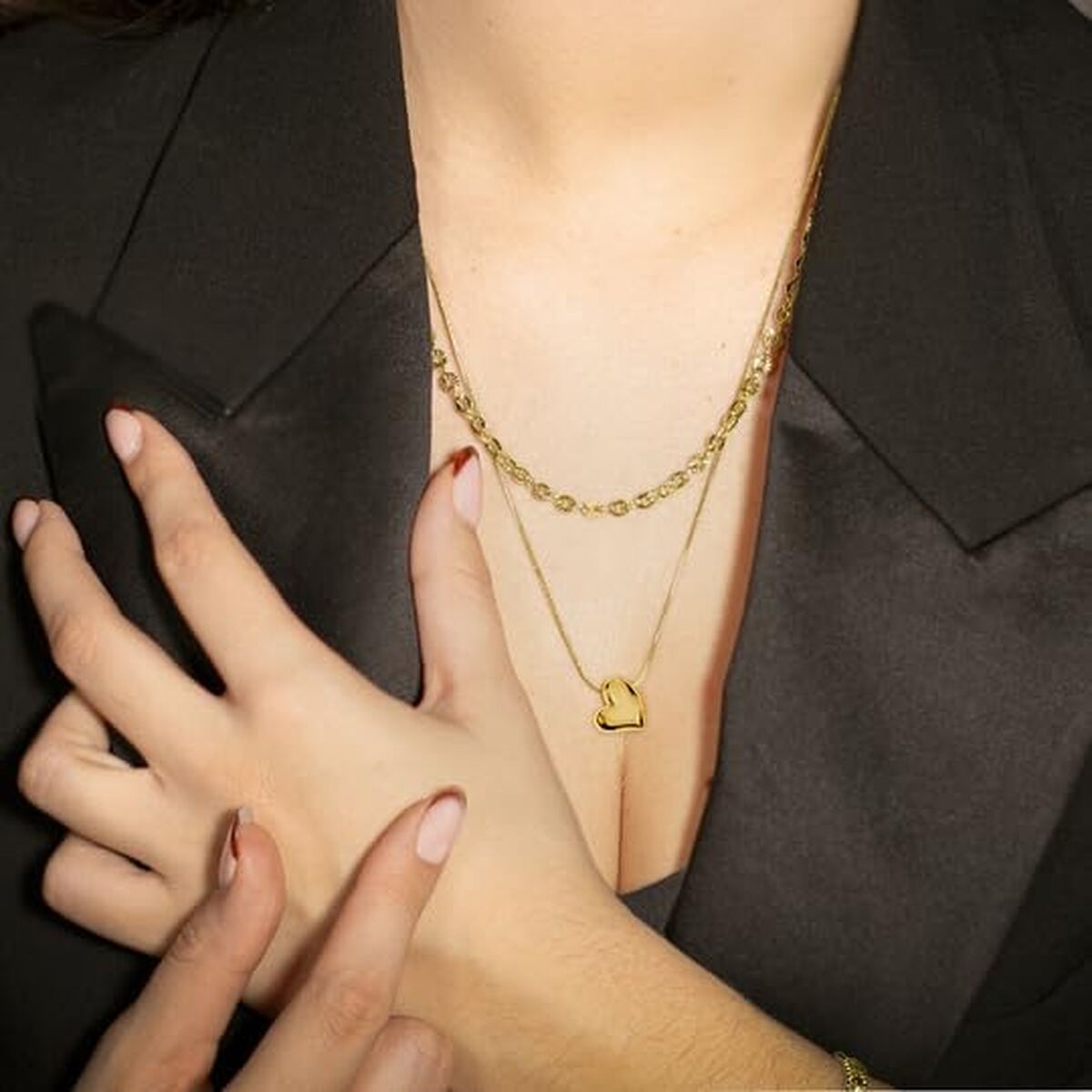 Detail van de gouden Lotus ketting met hartje, gedragen op een zwarte blouse.