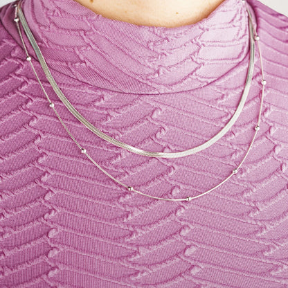 Detail van de zilverkleurige Lotus ketting met elegante schakel en kleine kralen.
