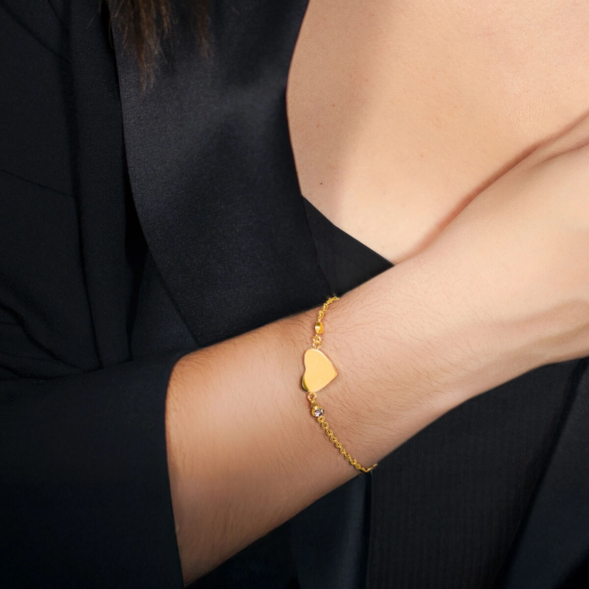Detail van de gouden Lotus armband met hartvormige hanger, elegant om de pols.