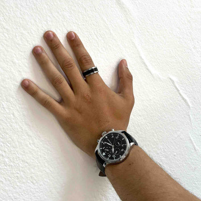 Zilverkleurige Radiant ring met zwarte details, gedragen op een hand naast een horloge.