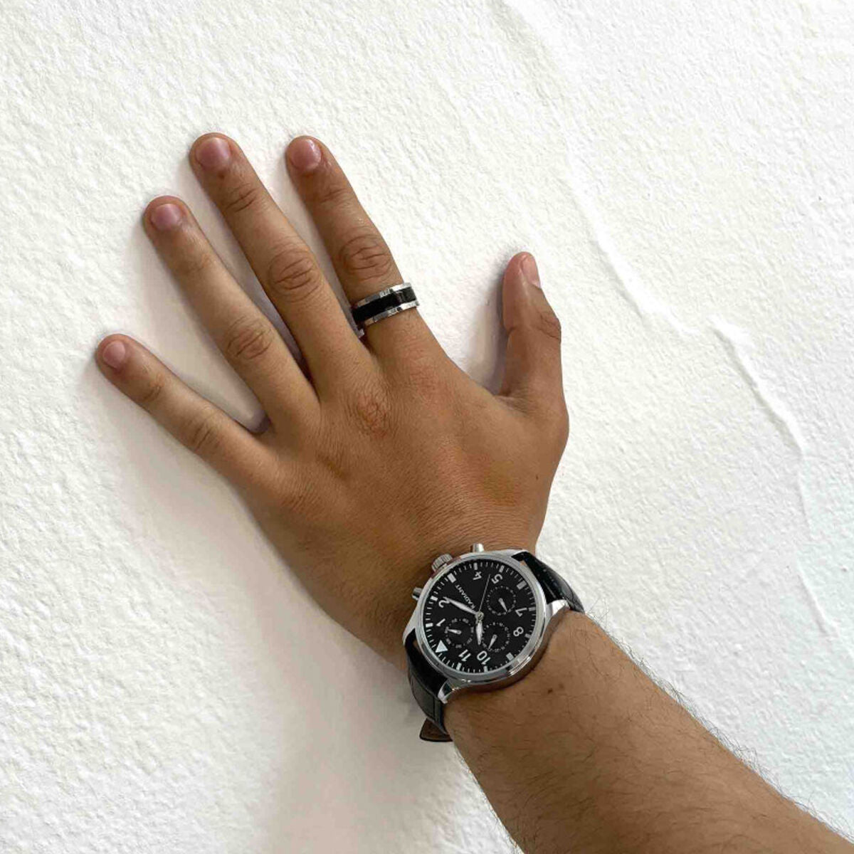 Zilverkleurige Radiant ring met zwarte accenten, gedragen op een hand met horloge.