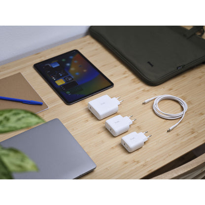 Detail van de Trust 25139 oplader met twee andere opladers en een USB-C kabel op een bureau.