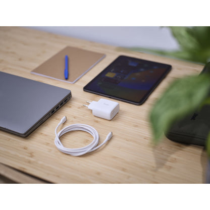 Trust Oplader 25139 Wit met USB-C kabel op een houten tafel naast een laptop en tablet.