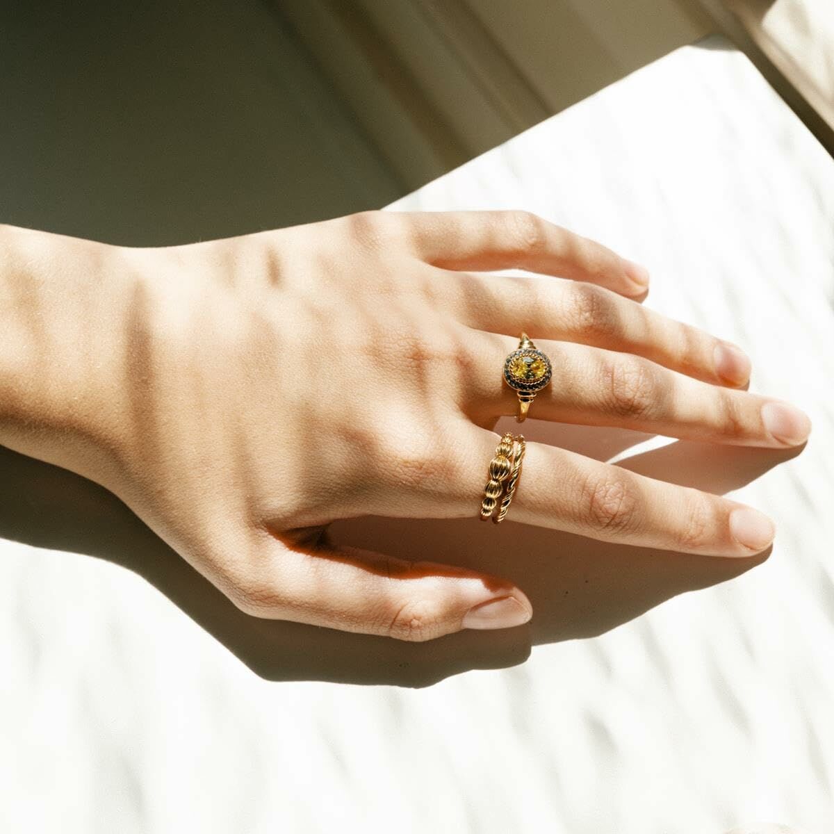 Detail van de 24KAE ring op een hand met een elegante gouden afwerking.