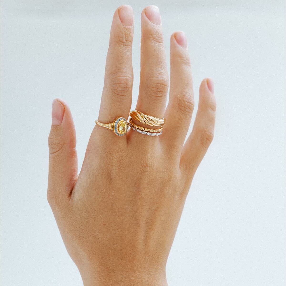 Detail van de 24KAE ring met elegant design, gedragen op een hand met andere ringen.