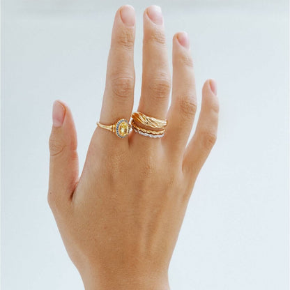 Detail van de 24KAE ring met elegant design, gedragen op een hand met andere ringen.