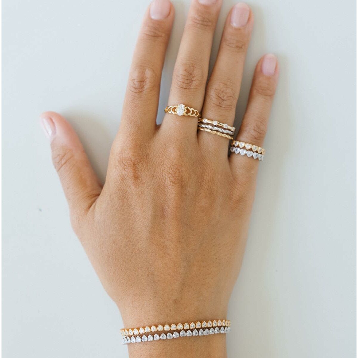 Detail van een hand met de zilverkleurige 24KAE ring, gecombineerd met andere elegante ringen.