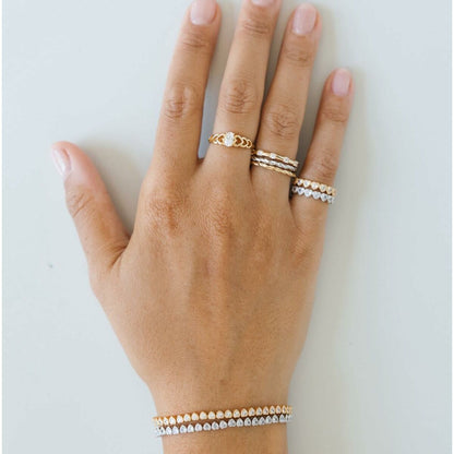 Detail van een hand met de zilverkleurige 24KAE ring, gecombineerd met andere elegante ringen.
