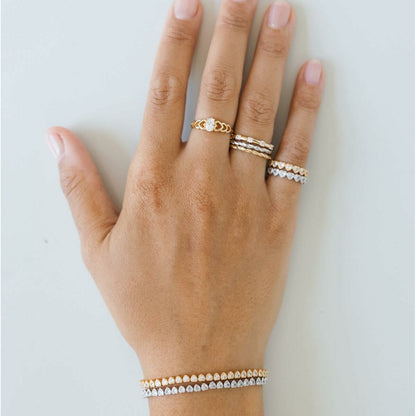 Detail van de 24KAE gouden ring, gedragen op een hand met meerdere sieraden.