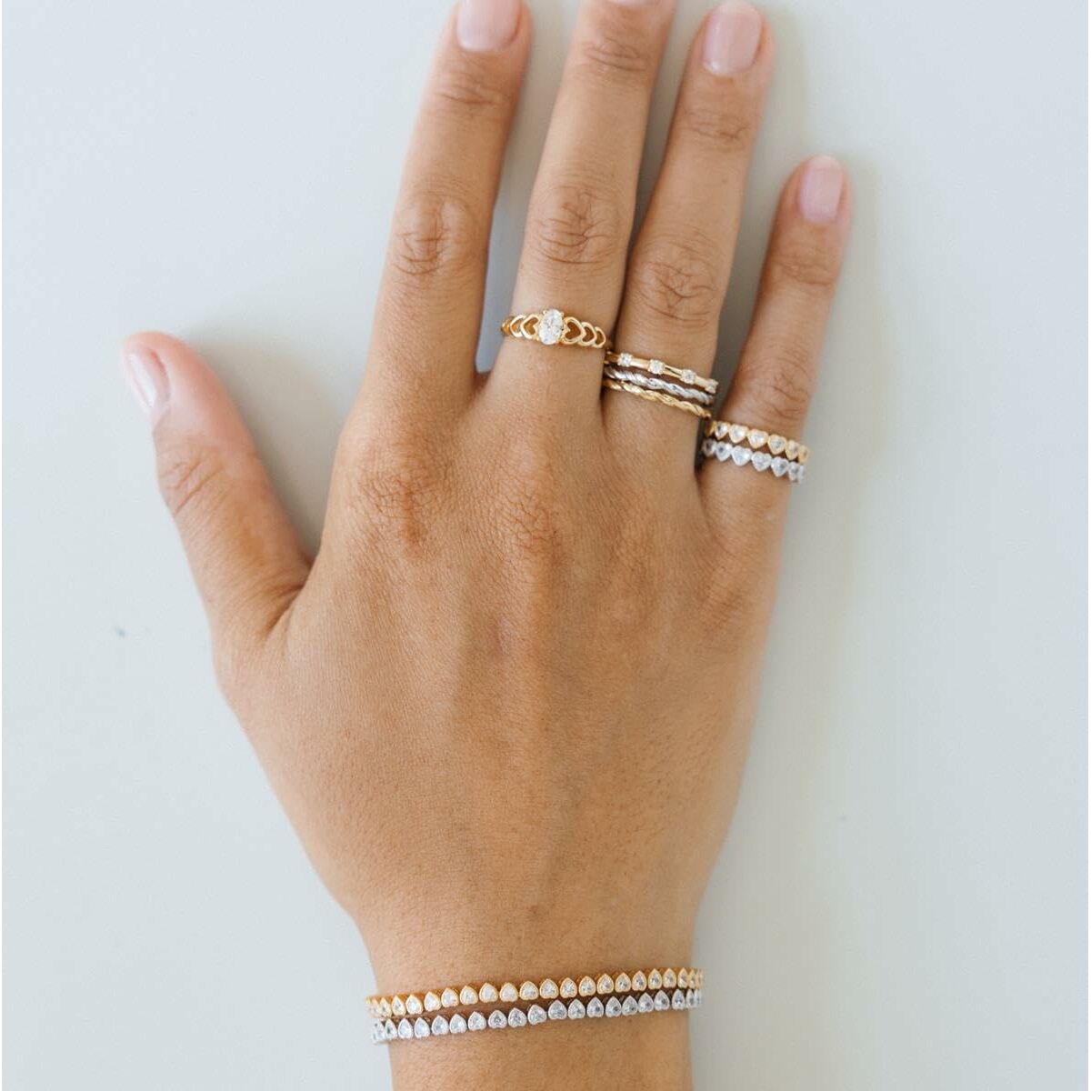 Detail van de 24KAE gouden ring gedragen op een hand met meerdere ringen.