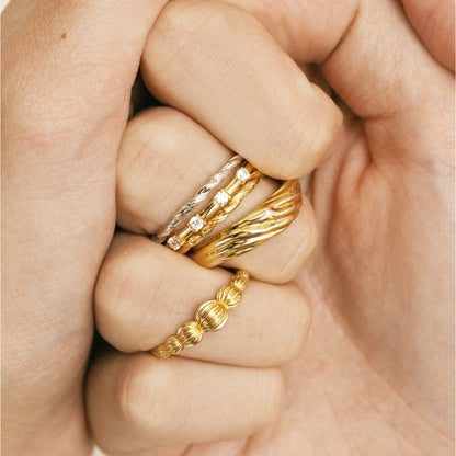 Detail van meerdere gouden ringen, waaronder de 24KAE ring met tijdloos design.