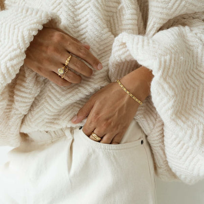 Detail van de 24KAE gouden ring, elegant gedragen met een lichte trui.