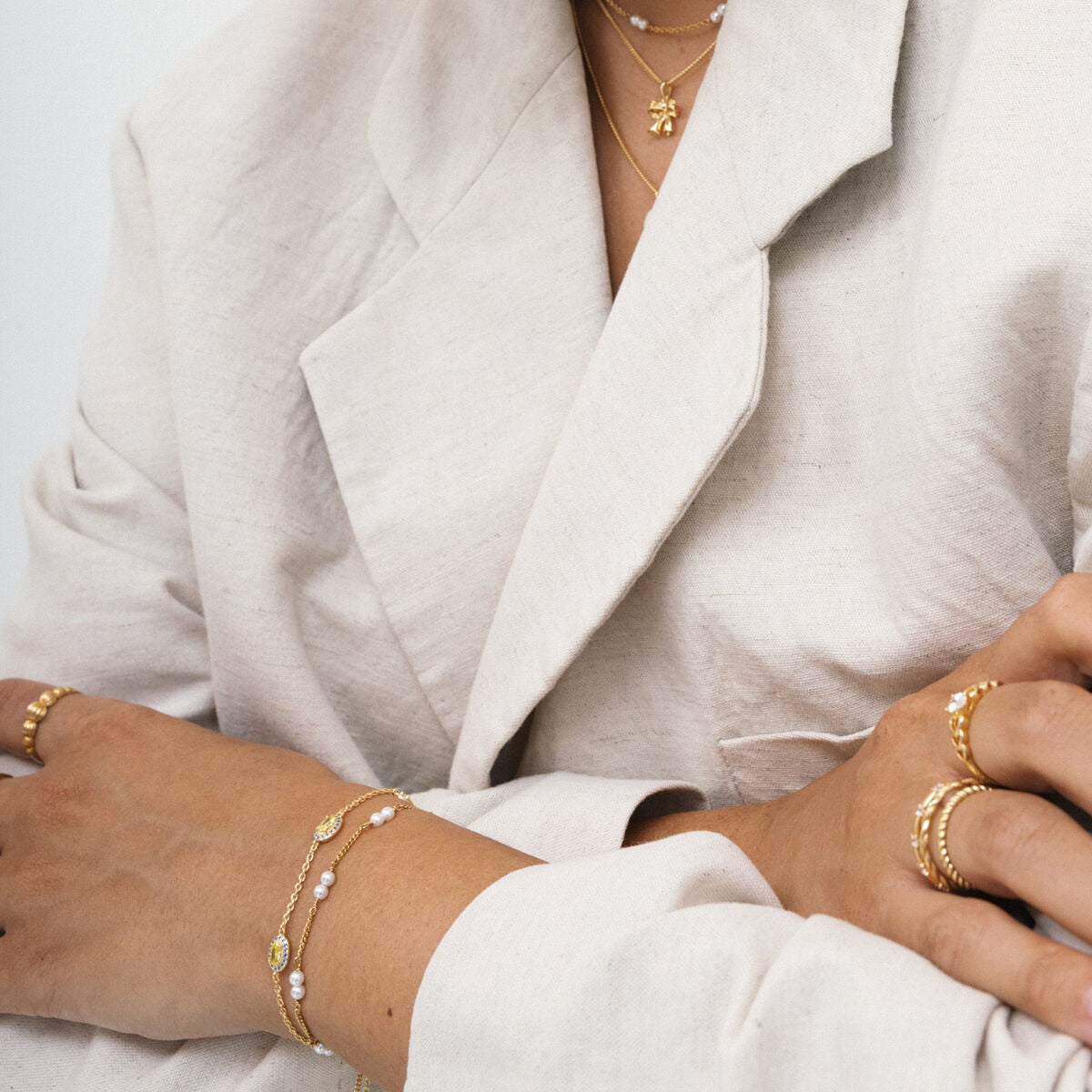Detail van de 24KAE gouden armband met elegante afwerking, gedragen met andere sieraden.
