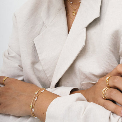 Detail van de 24KAE gouden armband met elegante afwerking, gedragen met andere sieraden.