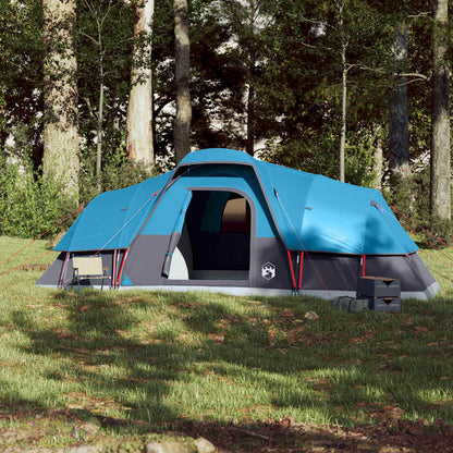 Zijaanzicht van de vidaXL koepeltent in blauw, geplaatst op gras met campingstoelen.