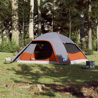 Zijaanzicht van de vidaXL koepeltent in grijs en oranje, op een groene campinglocatie.