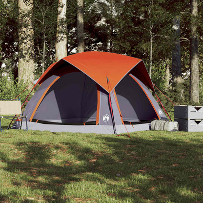 Zijaanzicht van de grijs-oranje vidaXL tent, op gras met bomen op de achtergrond.