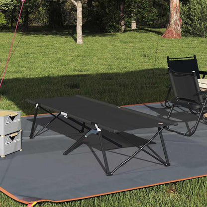 Opvouwbaar vidaXL campingbed in zwart, geplaatst op gras met campingstoelen.