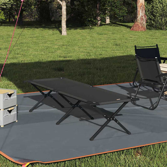 Zwart opvouwbaar campingbed van vidaXL, geplaatst op een grasveld met een campingstoel en opbergdozen.
