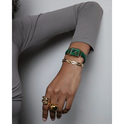 Detail van een hand met meerdere gouden Viceroy ringen en een groene horloge.