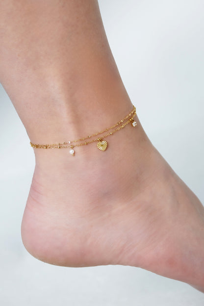Detail van het love love love enkelbandje van Festivalzone.com, met gouden schakels en hangende bedels.